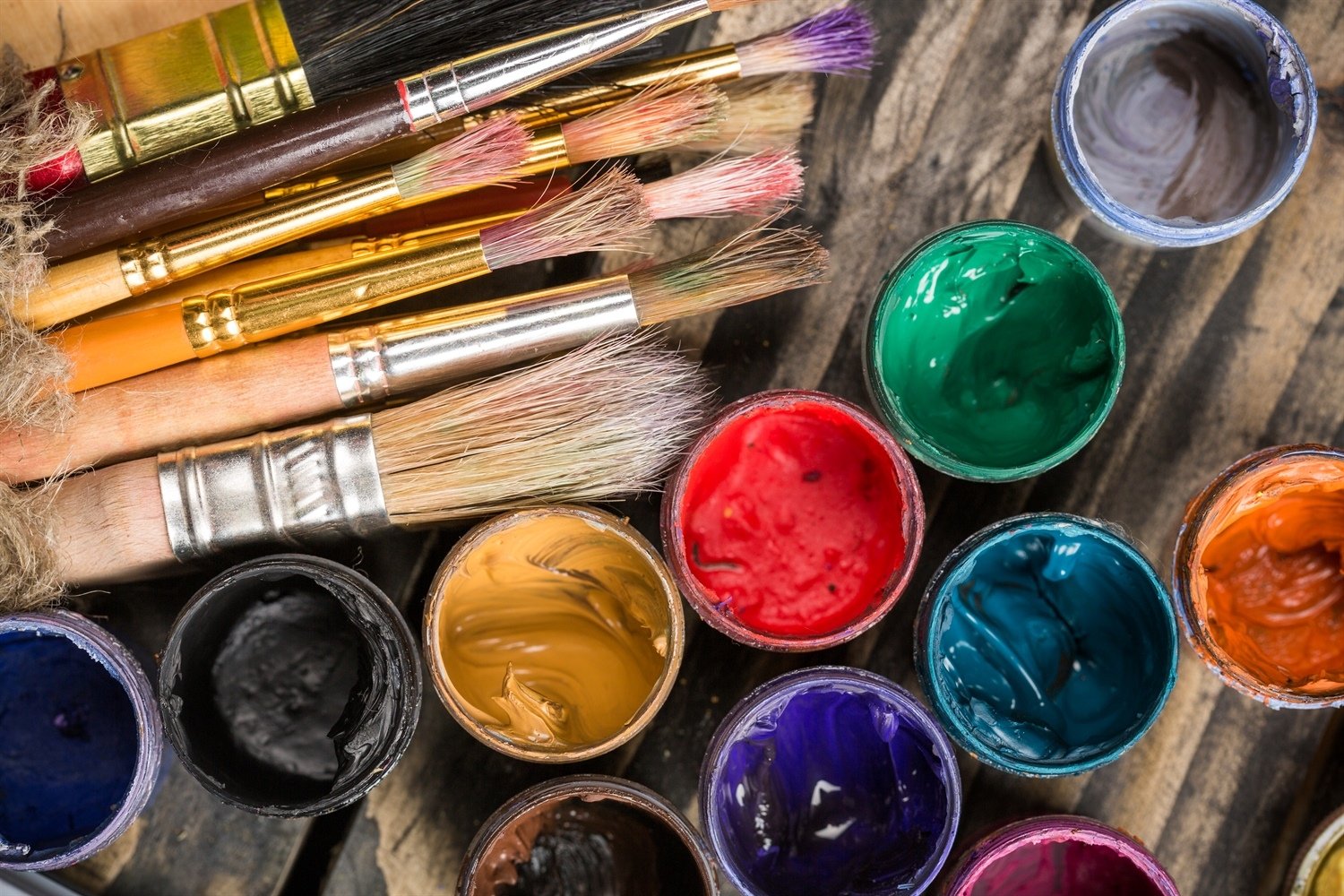 Bambini che dipingono sassi colorati su un tavolo, uno dei passatempi semplici per impegnarli